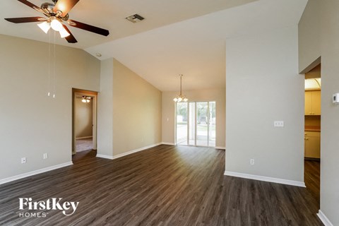 an empty living room with wood flooring and a ceiling fan
