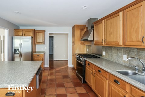 A kitchen with wooden cabinets and a tile floor.