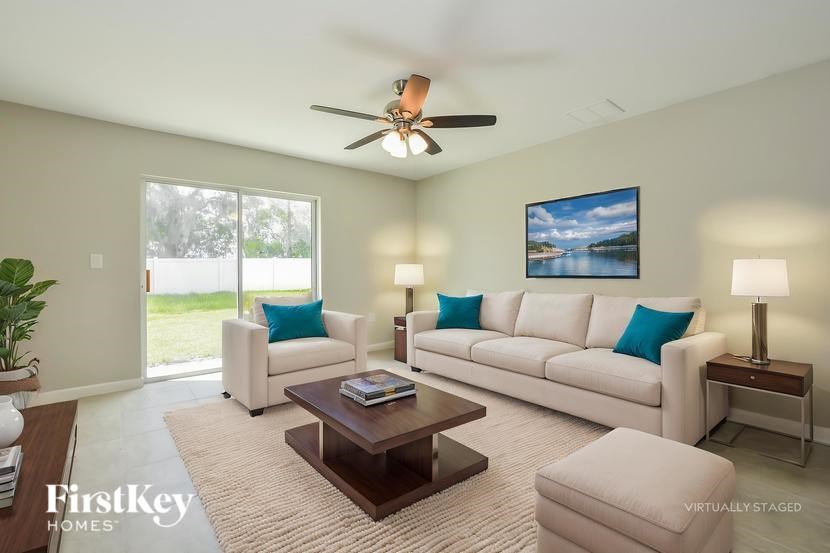 A living room with a white couch, a brown coffee table, and a ceiling fan.