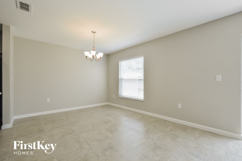 A room with a chandelier and a window with blinds.
