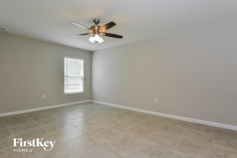 A room with a ceiling fan and a window with blinds.
