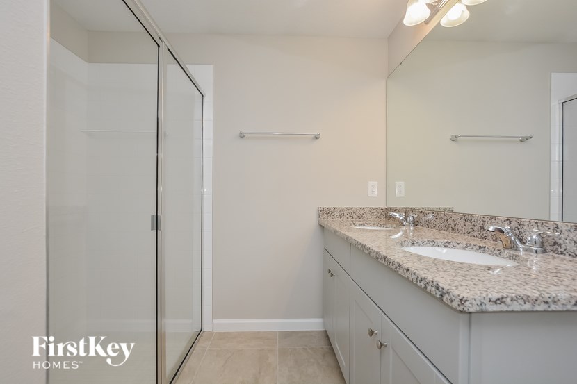 A bathroom with a granite countertop and a walk-in shower.