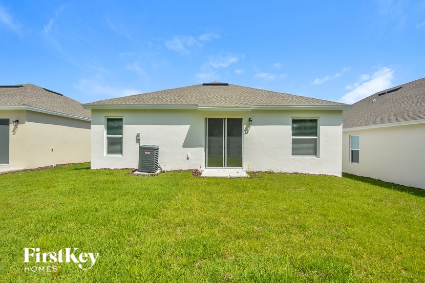 A white house with a brown roof and a green lawn in front.