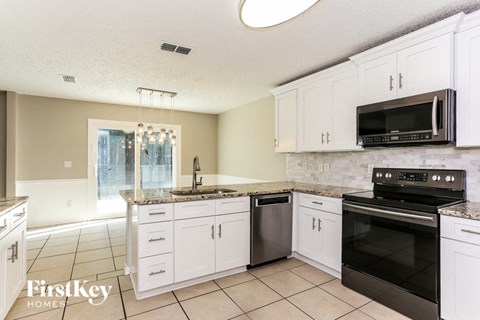 A kitchen with white cabinets and black appliances.