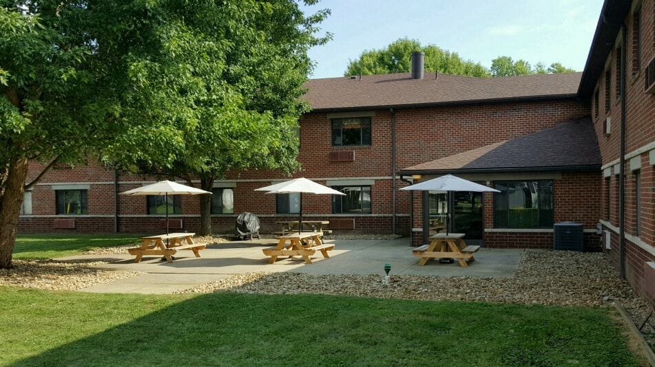 the back patio of a brick building with picnic tables and umbrellas