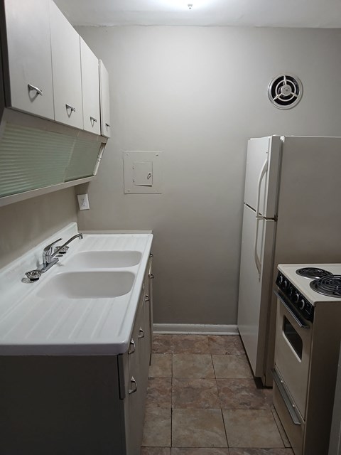 A small kitchen with a sink, stove and refrigerator.