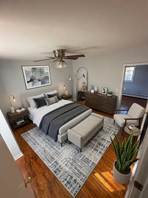 A bedroom with a bed, a chair, a potted plant, and a rug.