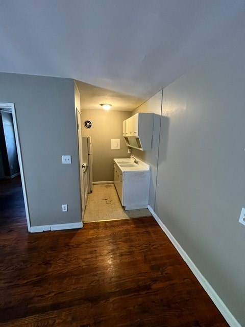 A kitchen area with a white fridge and a white sink.