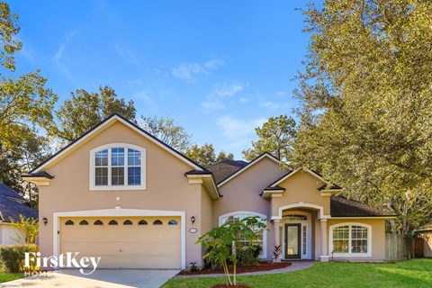 a beige house with a garage and trees