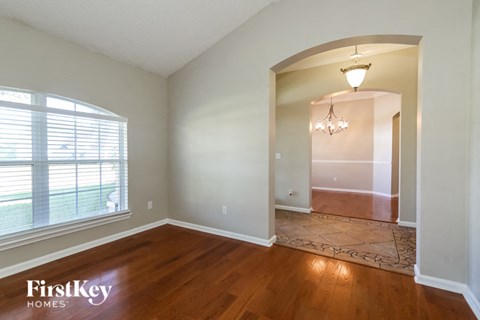 an empty living room with a large window and wood floor