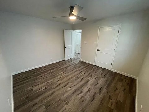 A room with wooden flooring and two white doors.