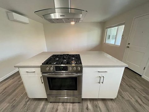 A modern kitchen with a stainless steel stove and white cabinets.