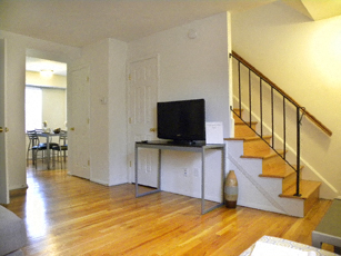 an empty living room with a tv on a table and a staircase
