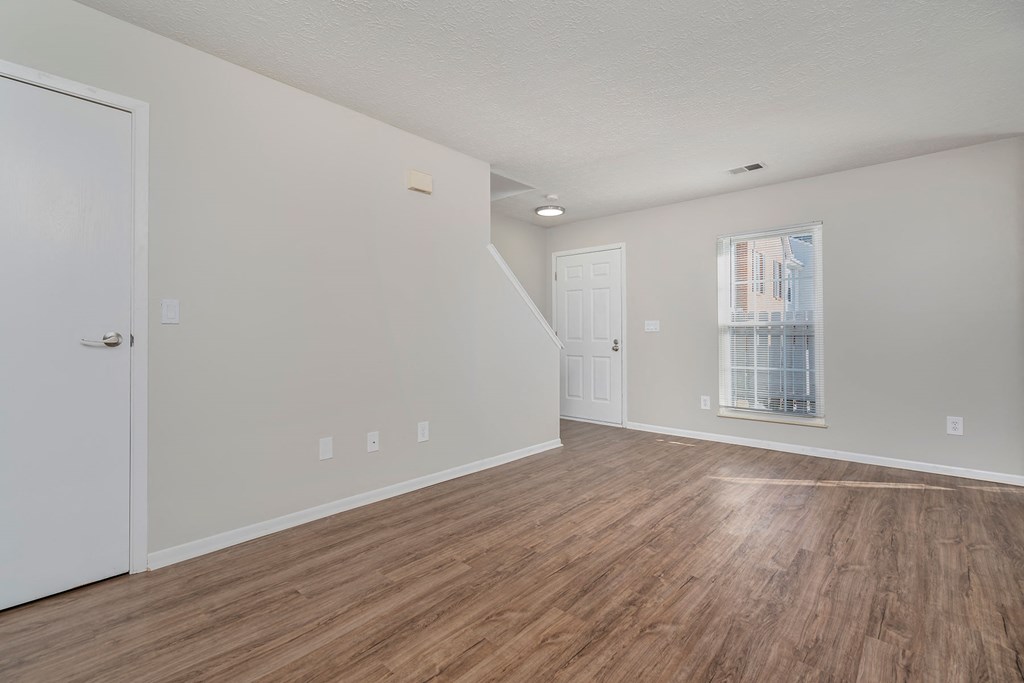 the living room and dining room of an apartment with wood flooring