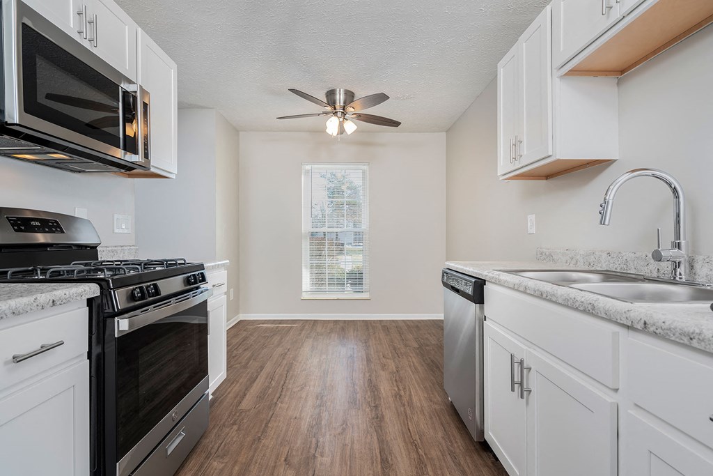 an empty kitchen with white cabinets and stainless steel appliances