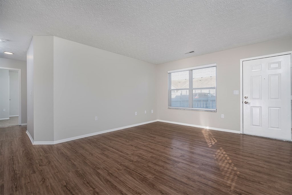an empty living room with wood flooring and a window