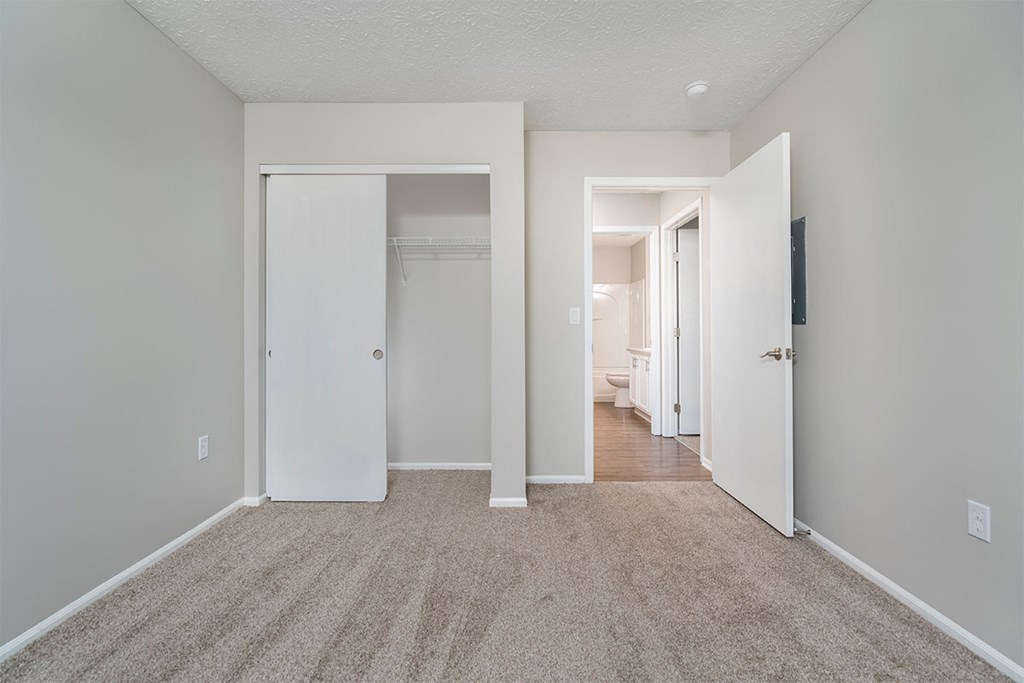 a bedroom with a carpeted floor and a door to a closet