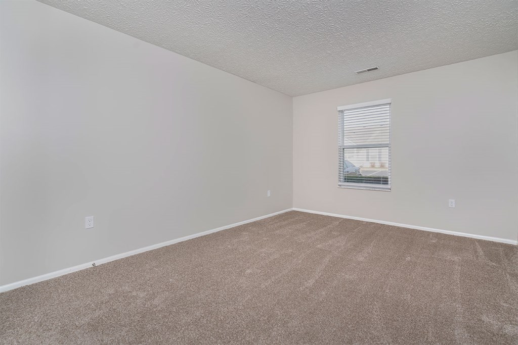 an empty room with carpet and a window