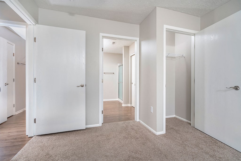 a bedroom with white doors and a hallway with closet doors