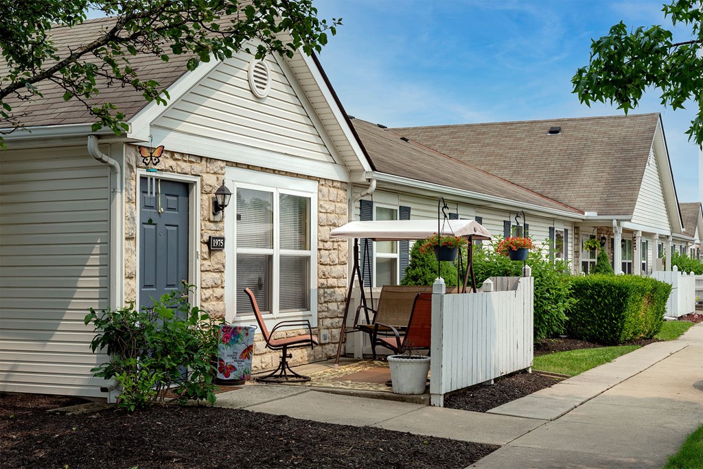 a white house with a blue door and a yard with a chair and an umbrella