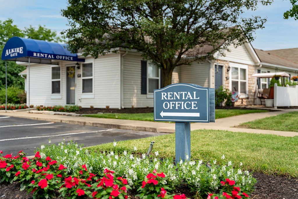 a rental office sign in front of a white building