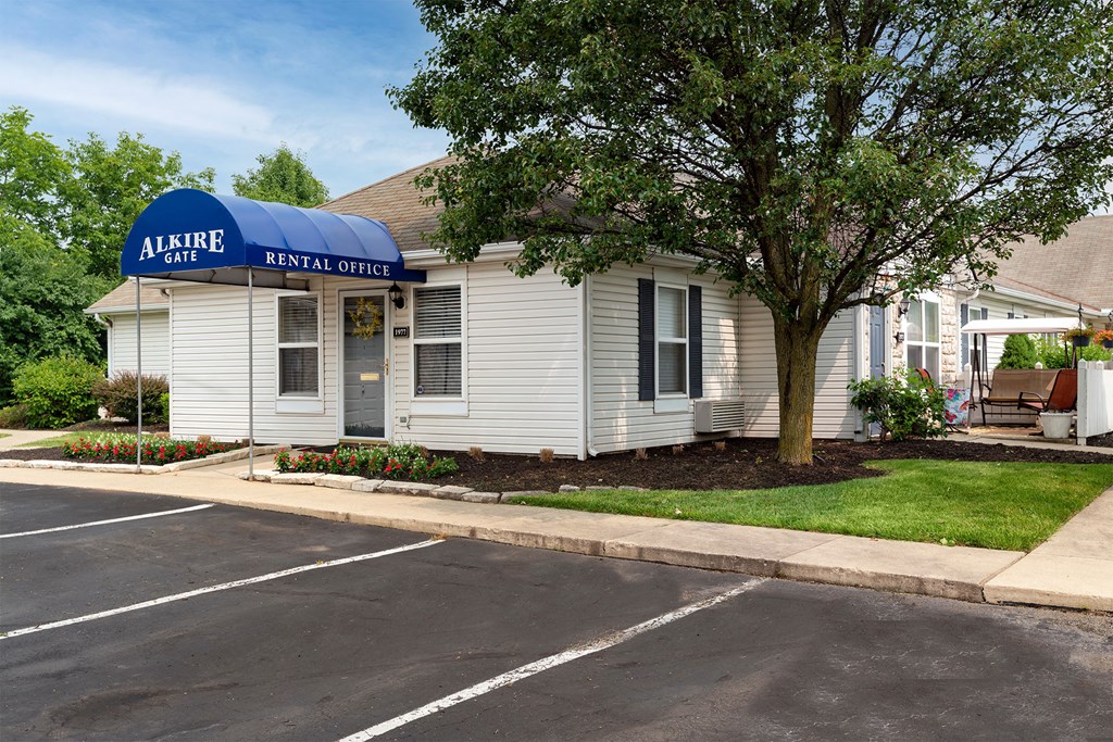 a white building with a blue roof and a tree in front of it