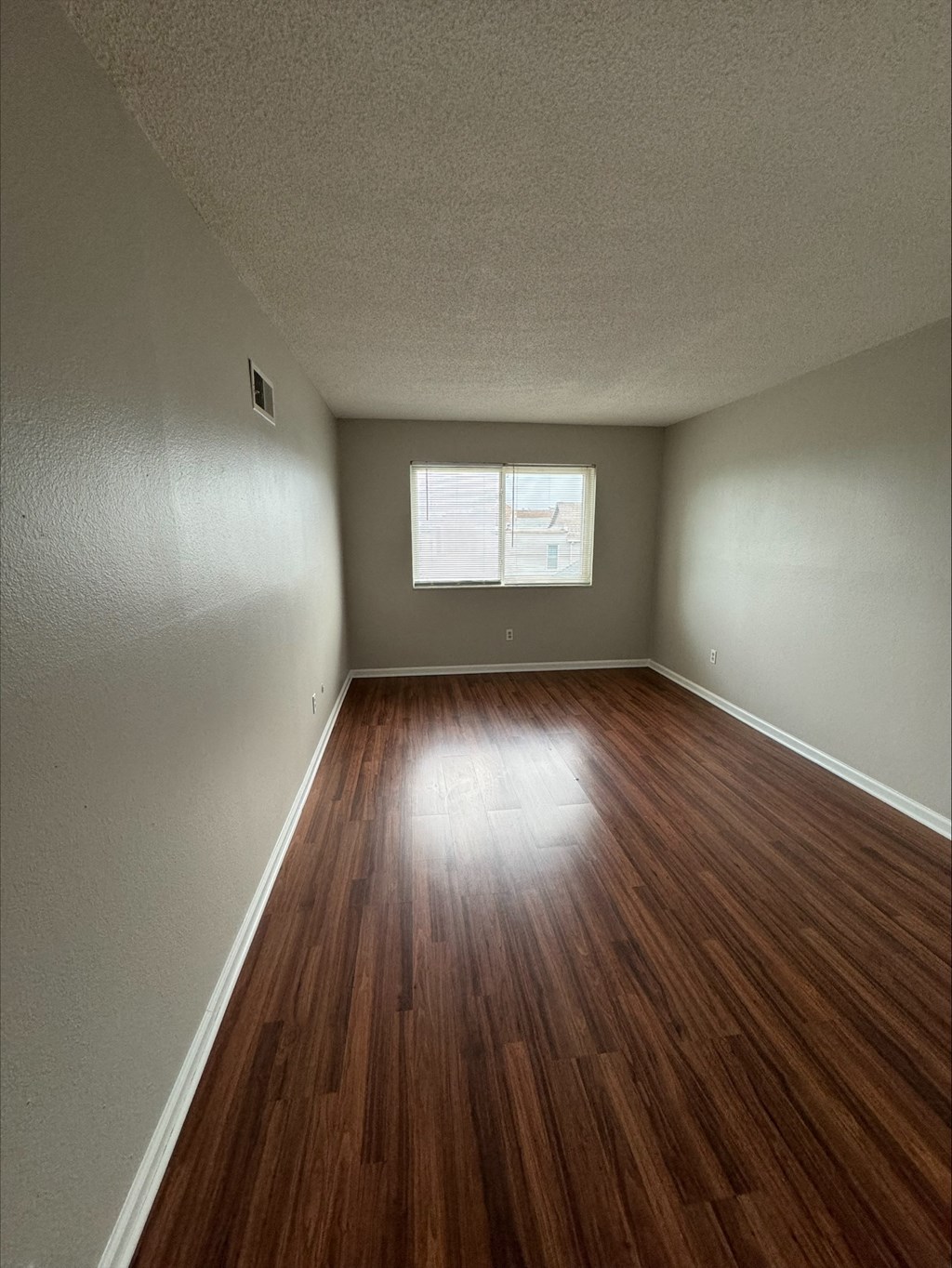 an empty room with wood floors and a window