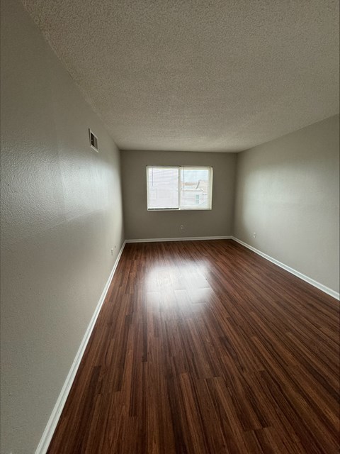 an empty room with wood floors and a window