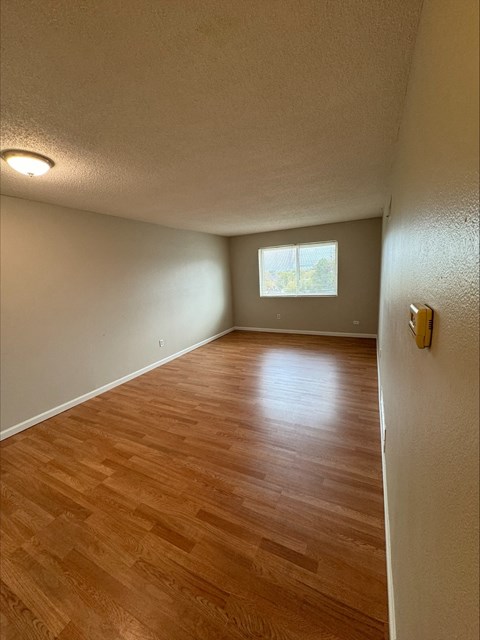 an empty living room with wood floors and a window