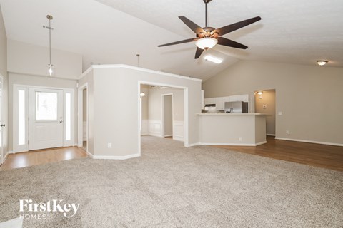 A spacious living room with a ceiling fan and a rug on the floor.