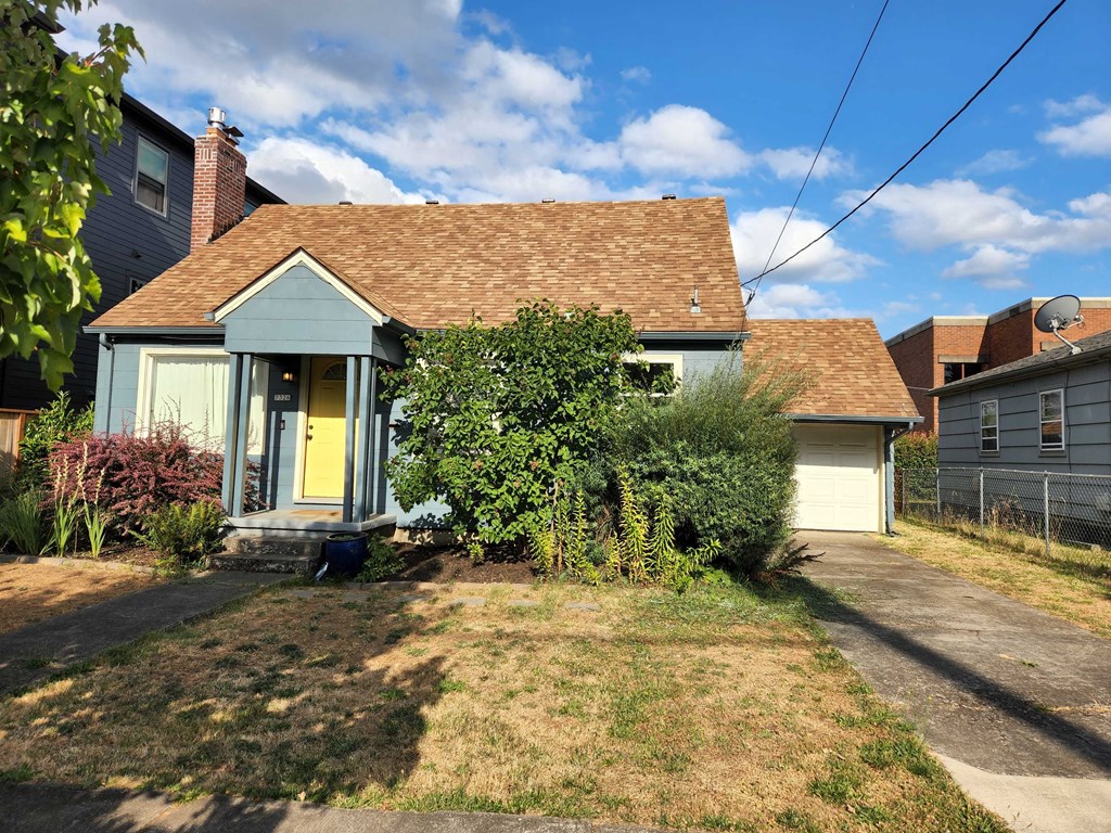 a small blue house with a yard and a garage