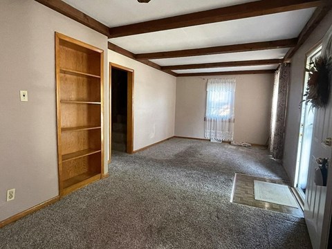 a living room with a carpeted floor and a wooden door