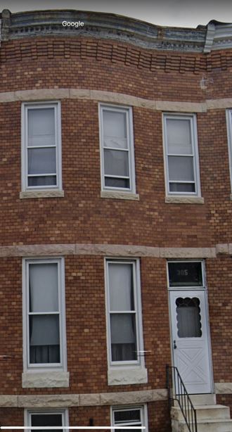 the front of a brick building with a white door and windows