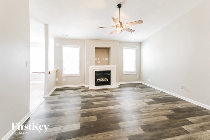 an empty living room with a fireplace and a ceiling fan
