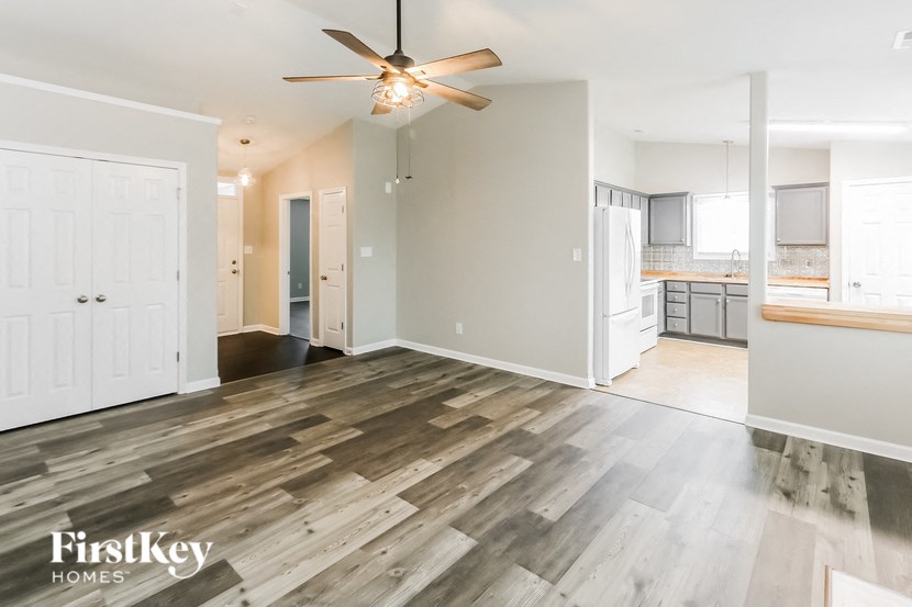 a living room and kitchen with wood flooring and a ceiling fan
