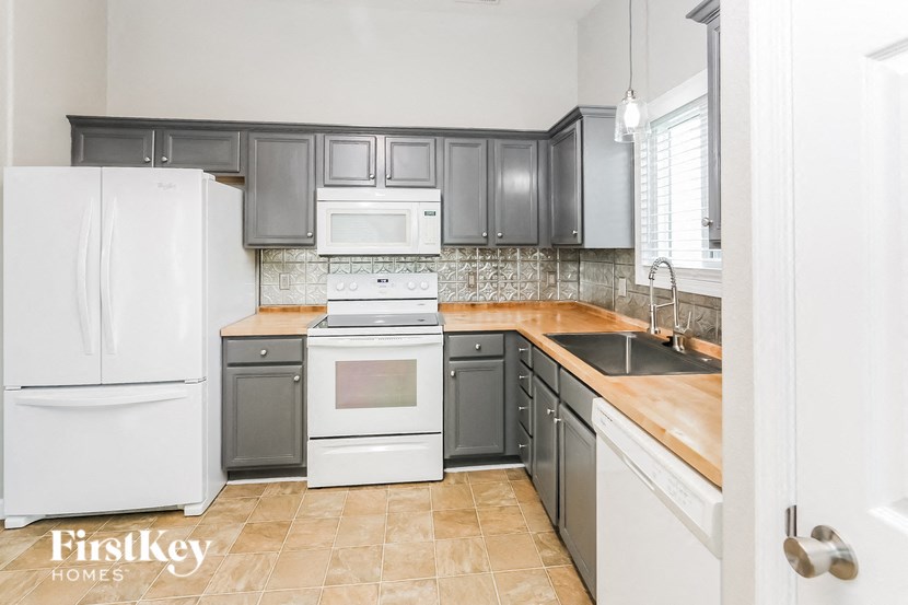 a kitchen with white appliances and gray cabinets