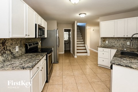 a kitchen with white cabinets and granite counter tops and a staircase
