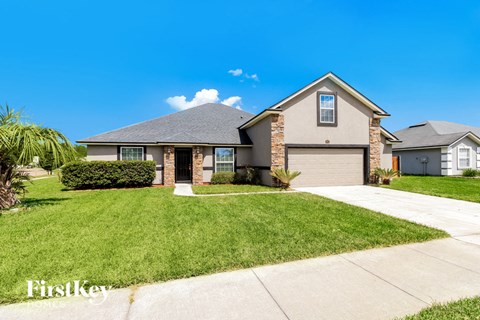 A house with a well-manicured lawn and a clear blue sky above.