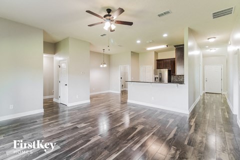 A spacious room with wooden flooring and a ceiling fan.