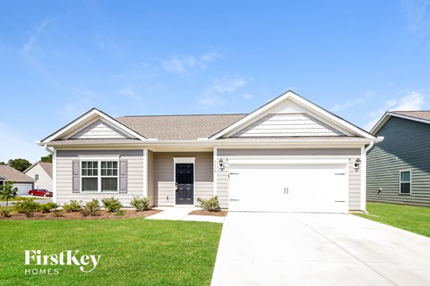 a white house with a garage door and a lawn
