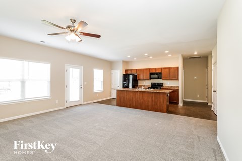 an empty living room and kitchen with a ceiling fan