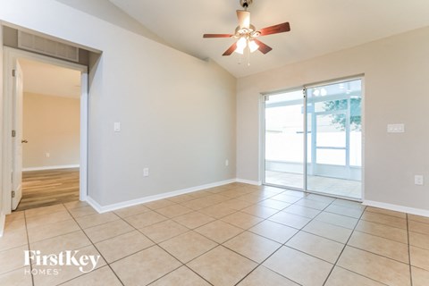 an empty living room with a ceiling fan and a sliding glass door