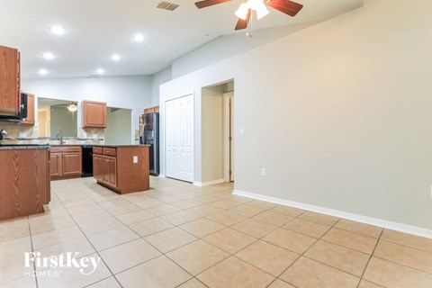 a kitchen and living room with tile flooring and a ceiling fan