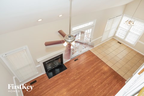 A wood floored room with a fan and a fireplace.