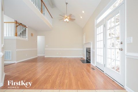 A spacious room with wooden floors and a ceiling fan.