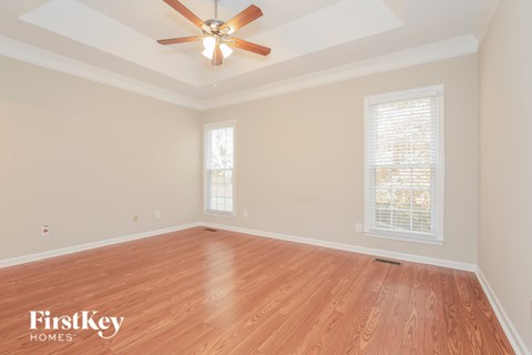 A room with a ceiling fan and wooden flooring.