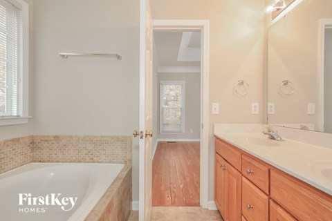 A bathroom with a tub, sink and mirror.