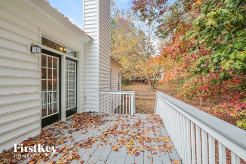 A white house with a porch covered in leaves.