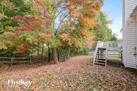 A white shed sits in a field of fallen leaves.