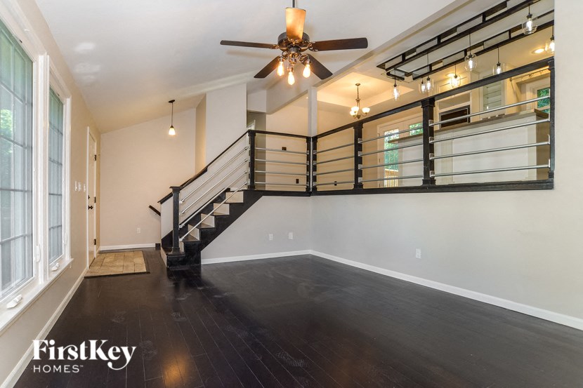 A spacious room with a staircase and a ceiling fan.